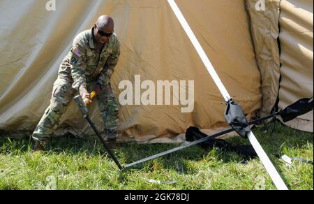 Comando Sgt. Il Major Sherman Waters, consigliere arruolato senior, 1° comando di sostegno del teatro truppe speciali Battaglione, martella un palo durante un esercizio di addestramento a Fort Knox, Kentucky, 23 agosto 2021. L'addestramento è stato progettato per aiutare i soldati a familiarizzare con il nuovo sistema di tenda e fare una valutazione sulle capacità future. Foto Stock