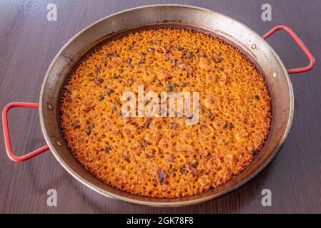 Paella in padella con riso calamaro su tavola di legno scuro Foto Stock