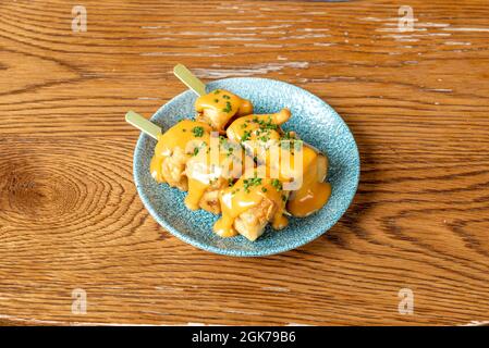 Spiedini di taco con melanzane fritte tempura e salsa al formaggio Cheddar e chiavette tritate Foto Stock