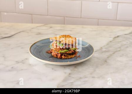 Sandwich di fettine di melanzane fritte a strati con ripieno di pollo e verdure su tavola di marmo Foto Stock