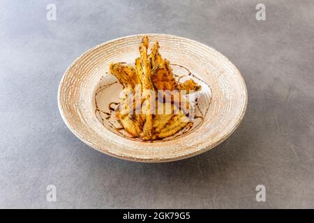 Fette di melanzana tempura con hummus di ceci e sciroppo di zucchero di canna su un piatto profondo Foto Stock
