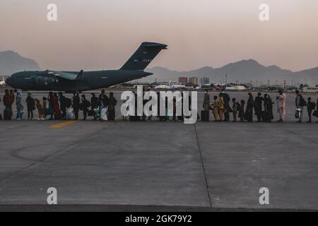 Gli evacuati attendono di salire a bordo di un Boeing C-17 Globemaster III durante un'evacuazione all'aeroporto internazionale Hamid Karzai, Kabul, Afghanistan, 23 agosto. I membri del servizio degli Stati Uniti stanno assistendo il Dipartimento di Stato con un'operazione DI evacuazione non combattente (NEO) in Afghanistan. Foto Stock