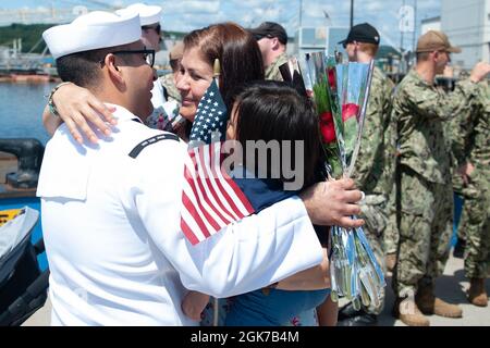 Ufficiale di Petty terza classe David Gutierrez abbraccia sua moglie Jackie e un figlio di un anno Sabastian momenti dopo USS San Juan (SSN 751) tornato a casa alla base sottomarina New London martedì 24 agosto 2021 dopo un dispiegamento di sette mesi. San Juan e l'equipaggio, che operavano sotto il Submarine Squadron (SUBRON) DODICI, tornarono a homeport da un dispiegamento programmato di sette mesi a sostegno della strategia marittima della Marina di sostegno degli interessi nazionali di sicurezza e delle operazioni di sicurezza marittima. Foto Stock