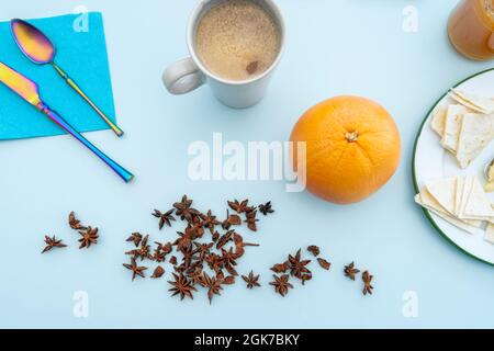 colazione sana con anice, caffè con latte d'avena, pompelmo maturo, cucchiai e forchette e pane acimo su tavola blu Foto Stock