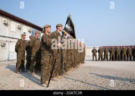 I membri del servizio lettone sono in piedi dalla Wolf Company guidon AS OF-3 Guntis Taurins, comandante, 1° Battaglione di fanteria meccanizzata, Brigata di fanteria delle forze terrestri, forze armate nazionali lettoni, offre osservazioni in occasione di una visita da Briga. Gen. Imants Ziedinš, vice comandante, forze armate nazionali lettoni, Camp Novo Selo, Kosovo, 24 agosto 2021. Foto Stock