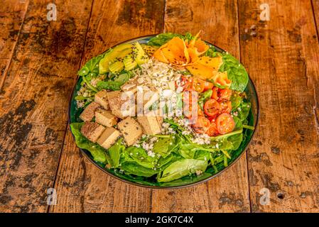 Ciotola di vegano con tofu tostato, mandorle a fette, pomodori ciliegini, spinaci verdi, zucca a fette, avocado e quinoa bianca cotta con semi di papavero nero Foto Stock