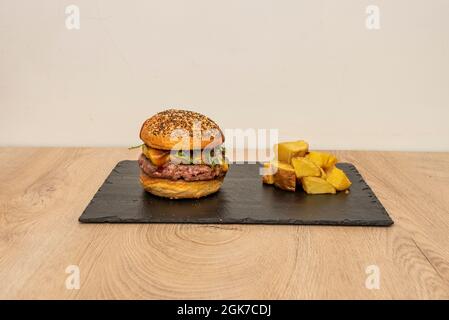 Hamburger di manzo classico con rucola, formaggio cheddar, cipolla e ketchup e senape e un lato di patatine fritte Foto Stock