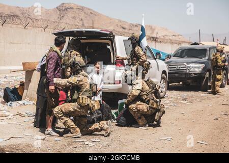 Le forze della coalizione finlandese assistono gli sfollati per il trattamento successivo durante un'evacuazione all'aeroporto internazionale Hamid Karzai, Kabul, Afghanistan, 24 agosto. I membri del servizio degli Stati Uniti e le forze di coalizione stanno assistendo il Dipartimento di Stato con un'operazione di evacuazione non combattente (NEO) in Afghanistan. Foto Stock