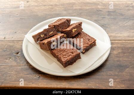 brownie al cioccolato con frutta secca e noci su carta greaseproof e piatto bianco Foto Stock