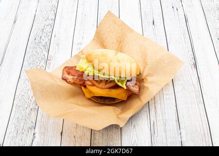 Hamburger di manzo con pane artigianale, strisce di pancetta fritte, formaggio cheddar fuso, anelli di cipolla cruda, lattuga e sottaceti, ketchup e senape Foto Stock