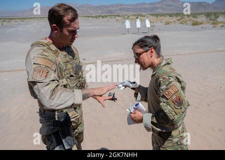 Airman 1st Class Brianna Middel, medic di squadra assegnato al 99th Tactical Response Team, fornisce cure mediche al personale Sgt. Lucas Hurt, la 99a squadra del Tactical Response Team, durante un'esercitazione avanzata di combattimento all'Air Force base di Nellis, Nevada, 31 agosto 2021. Durante questo corso, Airmen è stato messo in scenari che richiedono continue transizioni dalla loro arma primaria alla loro arma secondaria, utilizzando al contempo l'analisi e l'acquisizione rapide delle minacce per coinvolgere più bersagli e varie angolazioni. Foto Stock