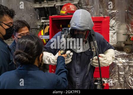 PORTO DI APRA, Guam (agosto 28, 2021) marinai assegnati alla nave da combattimento litoranea Independence-Variant USS Jackson (LCS 6) assistono Gunners Mate 1st Class Nicholas Rios, da Phelan, California, con il suo equipaggiamento da combattimento nella baia della missione. Jackson, parte di Destroyer Squadron Seven, è in fase di implementazione rotazionale, che opera nell'area operativa della settima flotta degli Stati Uniti per migliorare l'interoperabilità con i partner e fungere da forza di risposta pronta a sostegno di una regione indopacifica libera e aperta. Foto Stock