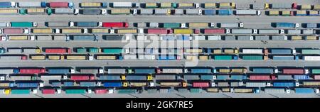 Vista aerea dei camion colorati nel terminal in attesa di scarico. Vista dall'alto del centro logistico. Foto Stock