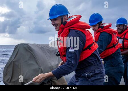 MAR DELLE FILIPPINE (ago. 29, 2021) i marinai a bordo del cacciatorpediniere missilistico guidato di classe Burke di Arleigh USS Barry (DDG 52) erigono una linea durante un rifornimento in mare con la nave da carico a secco di classe Henry J. Kaiser USNS Yukon (T-AO 202) come parte DI MALABAR 2021. Barry è attualmente schierato a sostegno del Commander, Task Force (CTF) 71/Destroyer Squadron (DESRON) 15, il più grande DESRON schierato in avanti della Marina e la principale forza di superficie della 7a flotta statunitense. Foto Stock