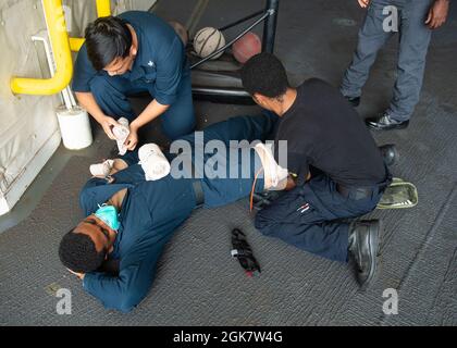 210830-N-LK667-0008 OCEANO ATLANTICO (AGOSTO 30, 2021) Specialista culinario 3a classe Angel A. Sandoval, left, e Seaman Apprentice Kyonte C. Washington, Right, Treat Aviation Boatswain's Mate (Airman Handling) Airman Antoine N. Harris' lesioni simulate durante un trivello di addestramento di massa a bordo della base del mare di Expeditionary USS Hershel 'Woody' Williams (ESB 4), 30 agosto 2021. Hershel 'Woody' Williams è in fase di dispiegamento programmato nell'area della Sixth Fleet degli Stati Uniti di operazioni a sostegno degli interessi e della sicurezza nazionali degli Stati Uniti in Europa e Africa. Foto Stock