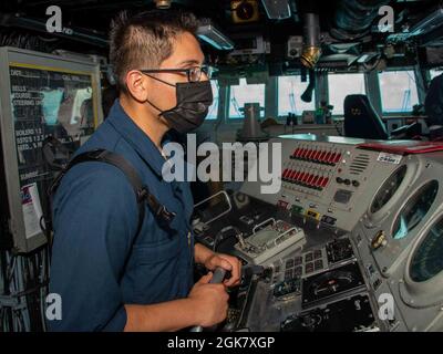 OCEANO PACIFICO (31 agosto 2021) Seaman Brian Maldonaldo, da Jacksonville, Flao., mans il timone della nave d'assalto anfibio USS Essex (LHD 2), 31 agosto. L'Essex, ammiraglia dell'Essex Amphibious Ready Group (ARG), insieme all'XI Marine Expeditionary Unit (MEU), opera nell'area di responsabilità della settima flotta statunitense per migliorare l'interoperabilità con alleati e partner e fungere da pronta forza di reazione per difendere la pace e la stabilità nella regione indopacifica. Foto Stock