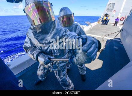 210831-N-MT581-1193 OCEANO PACIFICO (AGOSTO 31, 2021) marinai assegnati alla nave portuale di trasporto anfibio USS John P. Murtha (LPD 26) revisionare un incendio simulato sul ponte di volo durante l'esercizio Freedom Banner 2021, agosto 31. John P. Murtha partecipa a Exercise Freedom Banner, un esercizio annuale che prevede la proiezione strategica della forza di preposizionamento marittima (MPF) e delle forze di combattimento associate. Foto Stock