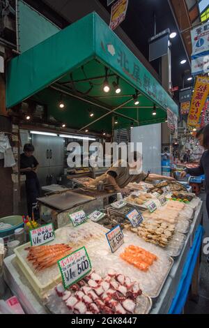 Bancarelle di pesce con prodotti appena pescati al mercato Kuromon Ichiba, Osaka, Giappone Foto Stock