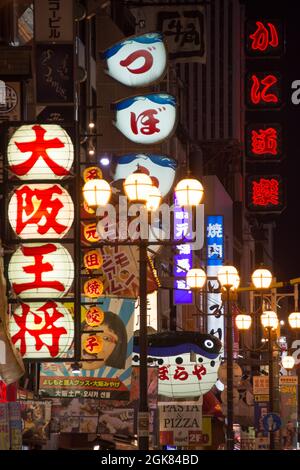 Cartellonistica giapponese sul fronte del negozio illuminata in serata lungo Dotonbori, Osaka, Giappone Foto Stock