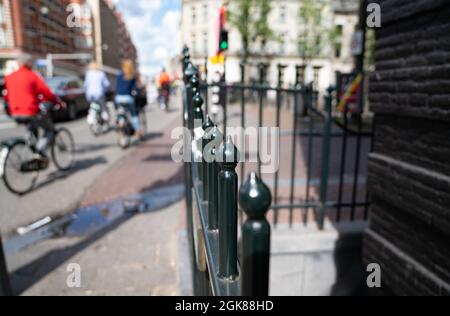 Immagine di sfondo sfocata e sfocata con balaustra in ferro battuto nella città di Amsterdam Paesi Bassi e ciclisti che passano. Foto Stock