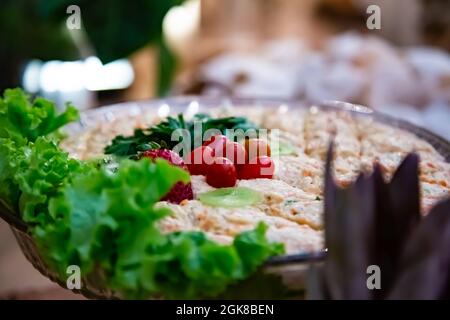 Tigela com salada. Alface, tomate, azeitonas e molho. Grande variedade de comida organizada em mesa de buffet Festiva. Foto Stock