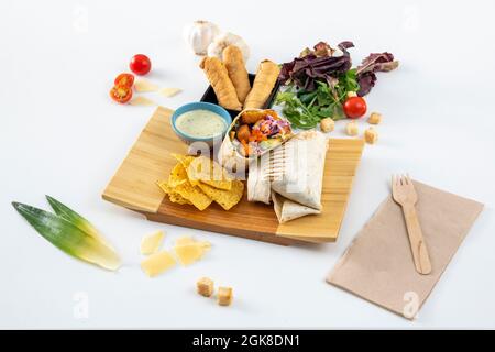 Burrito super e colorato con tortilla di grano, salsa verde, avocado e pollo fritto, colore viola e carota, mais nachos, tequeños venezuelano su w Foto Stock