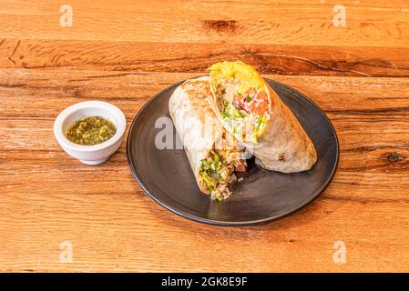 Grande burrito messicano ripieno di carnitas con riso e pico de gallo, salsa al peperoncino e tortilla di grano alla griglia Foto Stock