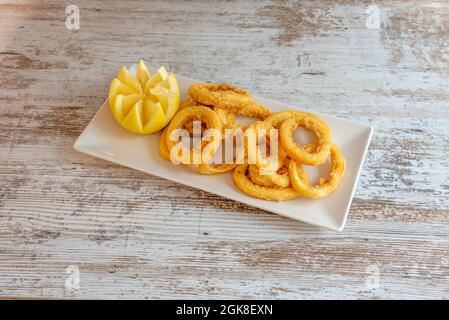 Calamari martoriati serviti su un piatto bianco in un ristorante di tapas spagnole con tavoli bianchi Foto Stock