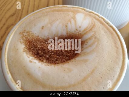 Cappuccino in una tazza con zucchero di canna, macro Foto Stock