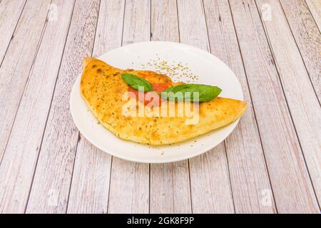 Ricetta italiana per calzone classico ripieni di prosciutto e formaggio con salsa di pomodoro e basilico Foto Stock