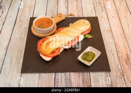 Sandwich italiano di insalata caprese con mozzarella a fette, fette di pomodoro e lattuga con salsa di ratatouille verde Foto Stock