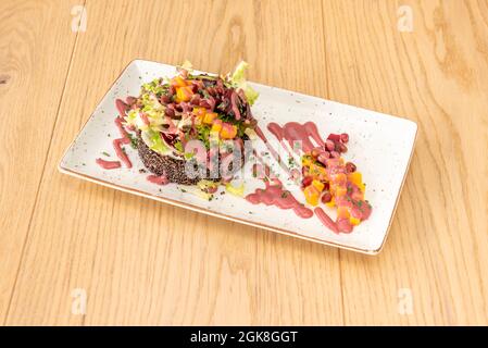 Insalata di quinoa nera cotta con grani di mango e melograno a dadini, salsa di indivia e fragola. Foto Stock