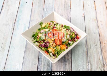 Insalata di verdure, pomodori ciliegini, tovoule, olio d'oliva all'interno di un recipiente quadrato bianco. Foto Stock