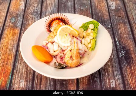 Ceviche miste di pesce e frutti di mare marinati con gamberi, cozze, calamari e capesante su un piatto bianco profondo Foto Stock