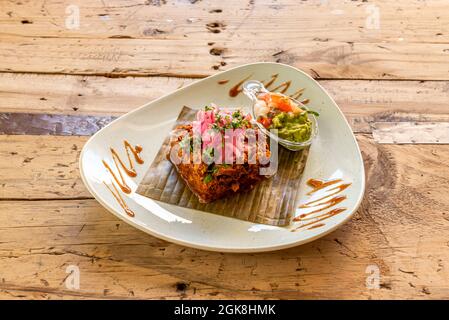 Deliziosa ricetta messicana del centro di cocinita pibil con un sacco di cipolla rossa, Pico de gallo e guacamole su foglia di banana Foto Stock