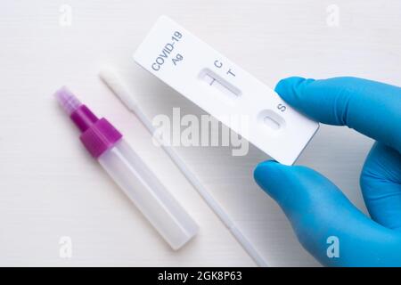 Test antigenico per coronavirus negativo e kit per diagnostica rapida in mano del medico con guanti di gomma su sfondo bianco Foto Stock