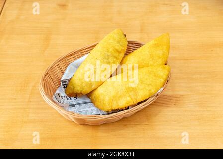 Cestino di vimini con razione di empanadas colombiane fatto con farina di mais gialla farcito con manzo stufato Foto Stock