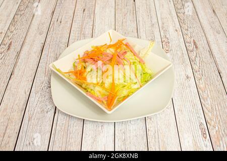 Insalata cinese con prosciutto, carota grattugiata, lattuga iceberg e strisce trasparenti su ciotola bianca Foto Stock