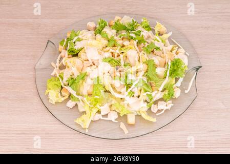 Ampia porzione di insalata Caesar con crostini, pollo e lattuga in un piatto di vetro trasparente Foto Stock