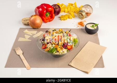 Insalata di Caesar con germogli di lattuga assortiti, pomodori ciliegini tagliati, scaglie di parmigiano e salsa di maionese su sfondo bianco Foto Stock