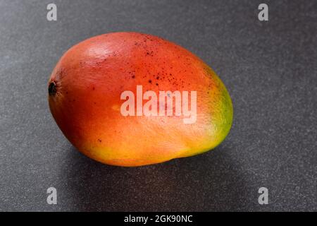 un mango maturo con un mix di toni rossi e arancioni Foto Stock