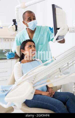 Dentista che mostra raggi X al paziente in clinica medica Foto Stock