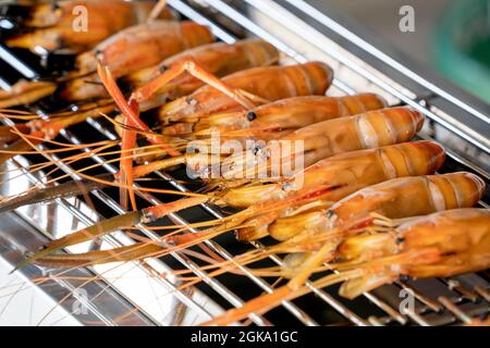 Primo piano Street food Thai gamberi barbecue sulla griglia. Thailandia Pesce gustoso con frutti di mare Tailandesi che immergere salsa piccante verde. Buon pranzo in vacanza estiva. Foto Stock