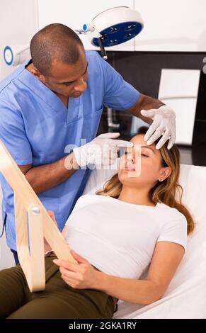 Donna di consulenza cosmetica maschile prima del trattamento viso Foto Stock