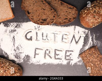 Senza glutine scritto in farina con diversi tipi di pane come decorazione, concetto di cibo sano Foto Stock