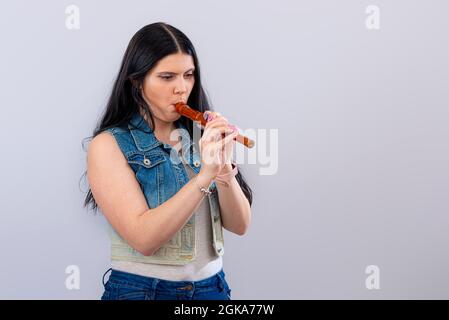 giovane adolescente dai capelli scuri che si erge su sfondo bianco e gioca flauto Foto Stock