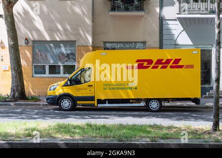 Vista laterale di un furgone elettrico DHL posto sul lato della strada Foto Stock