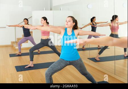 Giovane donna in piedi in affondo asana Virabhadrasana in studio yoga Foto Stock