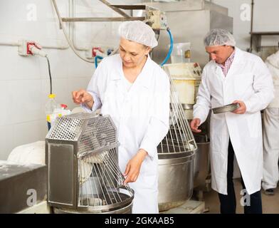 Panettiere che controllano la preparazione dell'impasto nella macchina impastatrice Foto Stock