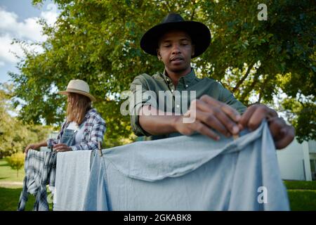 Misto razza maschio agricoltore appeso fuori sporca lavanderia all'aperto Foto Stock